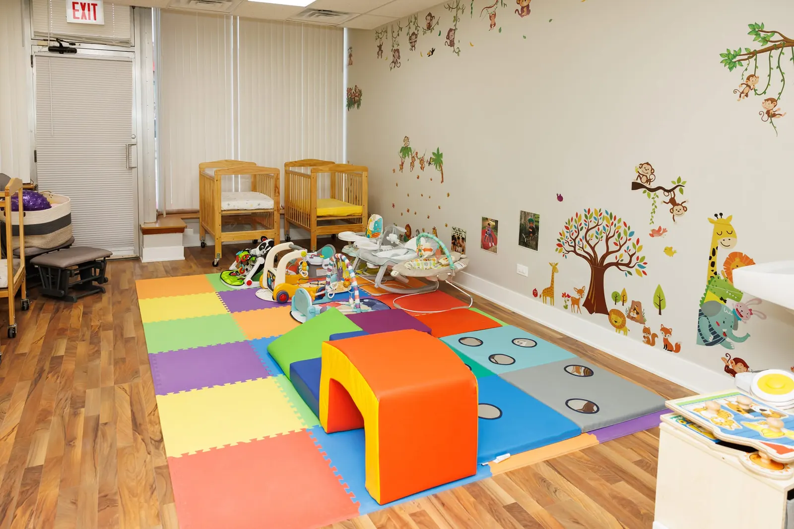 Infant room with cribs, a soft play tunnel and a foam floor