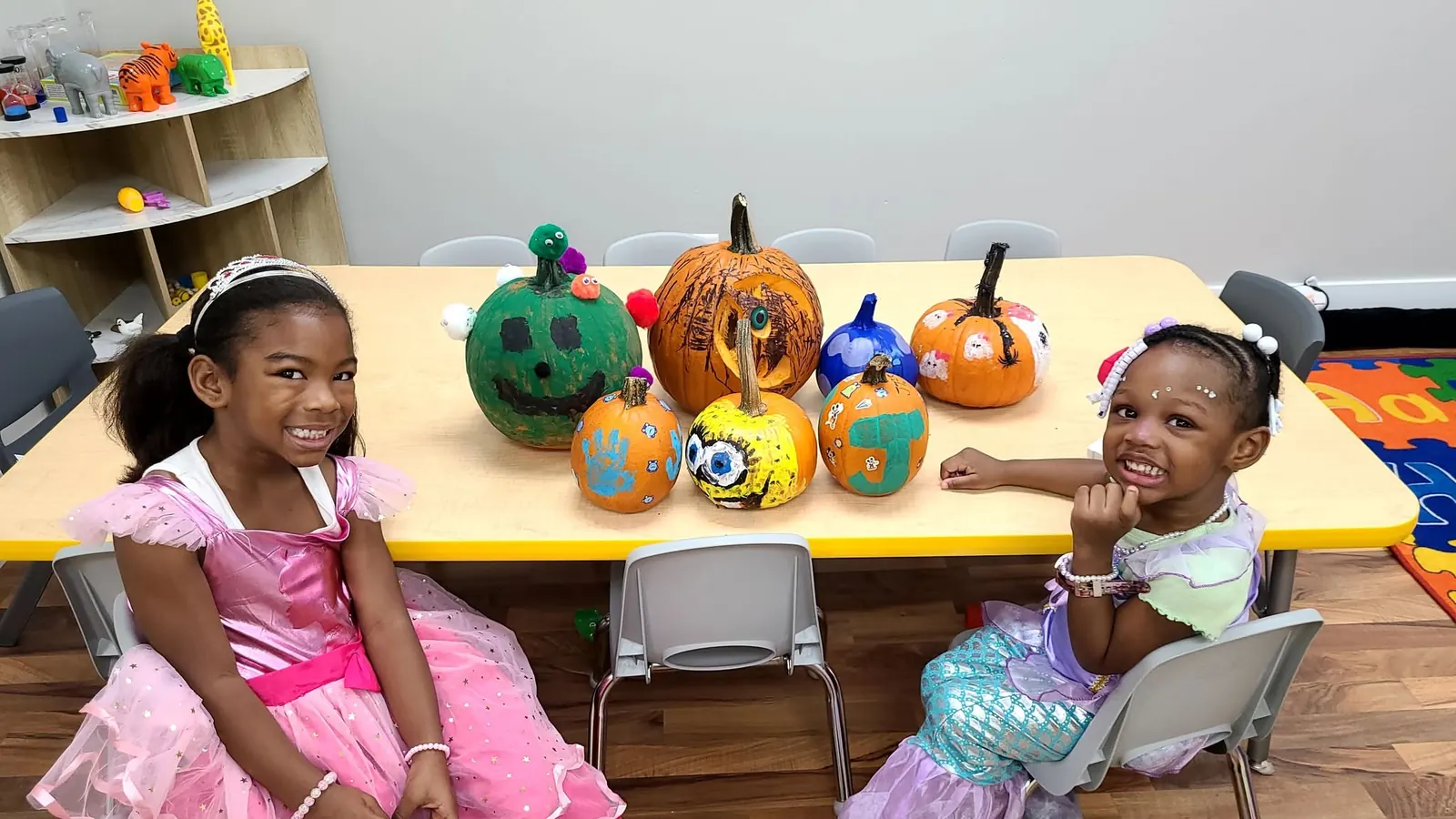 Two children with their decorated pumpkins at the art table