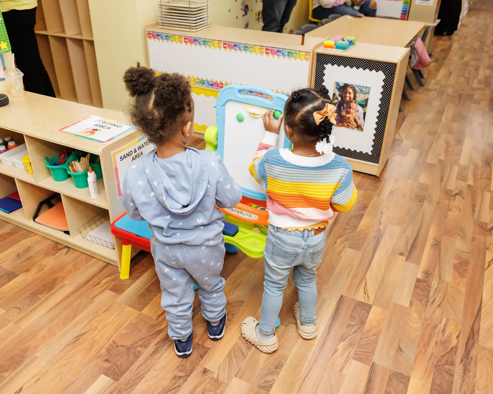 Two toddlers exploring a classroom easel together